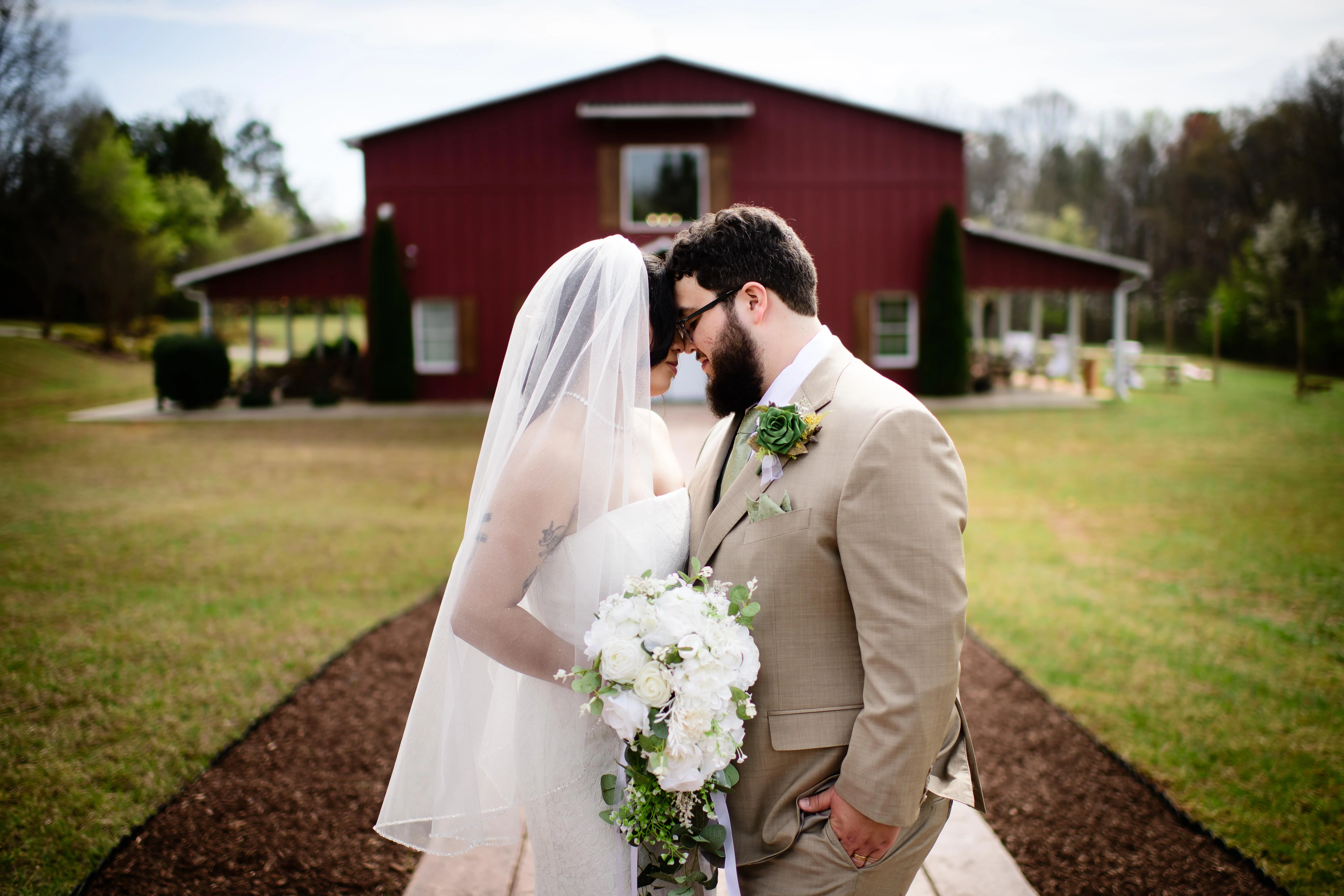 Couple standing close together on the walkway with the red barn in the background